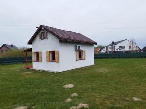 una pequeña casa blanca en un campo de hierba en Domek całoroczny, en Zastań