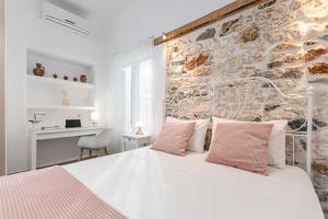 una camera da letto con un letto bianco e un muro di pietra di Villa Maro - Luxury Apartment a Naxos Chora