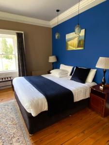 ein Schlafzimmer mit einem großen Bett mit blauer Wand in der Unterkunft Clone Country House in Aughrim