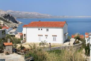 a white house with a red roof next to the water at Apartments with parking space Metajna, Pag - 208 in Metajna