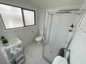 a bathroom with a shower and a toilet and a sink at Beach House @ Moffat in Caloundra