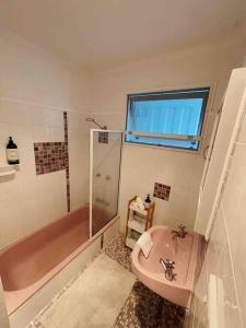 a bathroom with a pink tub and a sink at Beach House @ Moffat in Caloundra