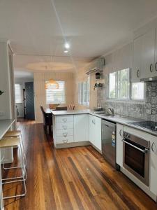 a kitchen with white cabinets and a wooden floor at Beach House @ Moffat in Caloundra