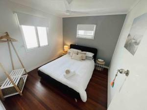um quarto com uma cama com lençóis brancos e 2 janelas em Beach House @ Moffat em Caloundra