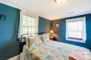 a blue bedroom with a bed and two windows at Victorian New Bern Vacation Rental In Downtown! in New Bern
