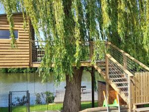 a tree with a wooden staircase next to a building at Gîte familial avec piscine privative chauffée, terrasse sur le Loir et proche du Zoo de La Flèche - FR-1-410-329 in La Flèche