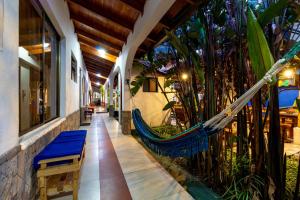 a porch with a hammock in a building with plants at Santa Cruz Backpackers Hostal in Baños