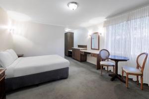 1 dormitorio con cama, escritorio y mesa en Elizabethan Lodge, en Melbourne