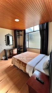 a bedroom with a large bed with a wooden ceiling at Vymar and Loto Azul in Pasto