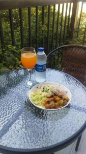 una mesa con un plato de comida y un vaso de zumo de naranja en raibrasil guest house, en Sanuki