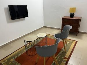 a living room with two chairs and a tv at Residence B&B Hibiscus in Dakar