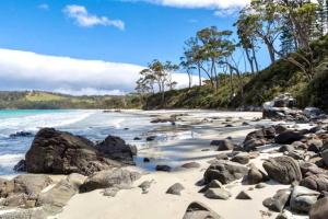 a beach with rocks and water and trees at 44onRoaring - in the Huon Valley in Surveyors Bay