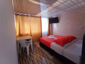 a bedroom with a red bed and a table and a desk at HOTEL BOGOTA AIRPORT DORADO in Bogotá