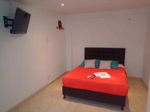 a bedroom with a red bed with a tv on the wall at HOTEL BOGOTA AIRPORT DORADO in Bogotá