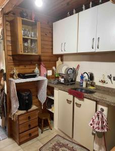 uma cozinha com armários brancos e uma bancada em Miramar Chalé e Suítes em Angra dos Reis