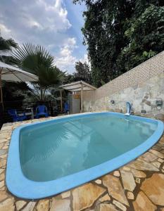 uma grande piscina num quintal com uma parede de pedra em Miramar Chalé e Suítes em Angra dos Reis