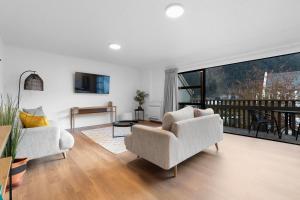 a living room with two chairs and a balcony at Location, Location in Queenstown
