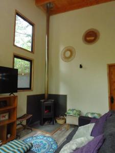 a living room with a bed and a stove at Cómodo chalet con tinaja rodeado de bosque nativo in Pucón