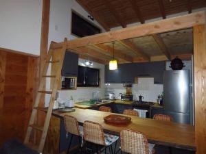 cocina con encimera de madera con sillas y escalera en Cómodo chalet con tinaja rodeado de bosque nativo en Pucón