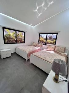 a bedroom with two beds and two windows at Beautiful Home and Pool near beach , BBQ Juan Dolio metro country Club in Juan Dolio
