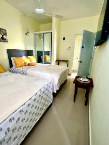 a bedroom with two beds and a table and a mirror at Hotel Maria Bonita Higüey in Higuey