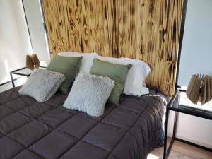 Una cama con almohadas verdes y blancas. en Aires de mar en Huerta Grande