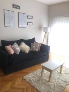 sala de estar con sofá negro y mesa en Apartamento amoblado de 2 ambientes completo en Buenos Aires