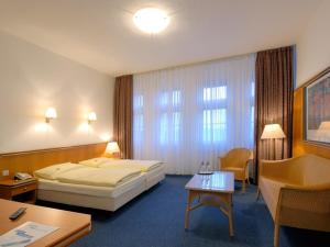 ベルリンにあるホテル ウント ラストフ アヴォスのベッドとテーブルが備わる広いホテルルームです。