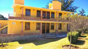 a yellow house with a balcony on top of it at Finca Marix in Villa del Carbón