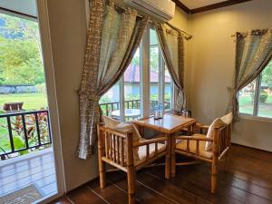 ein Esszimmer mit einem Tisch, Stühlen und Fenstern in der Unterkunft Bearlinbungalow in Vang Vieng