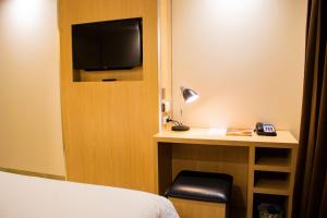 ein Hotelzimmer mit einem Bett und einem Schreibtisch mit einem TV in der Unterkunft Cassowary Hotel in Runai