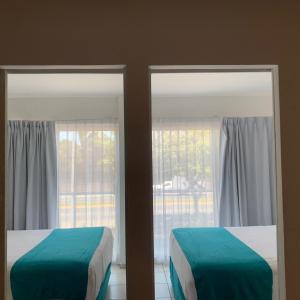 two beds in a room with two windows at Container Inn Hotel Aeropuerto in Puerto Vallarta