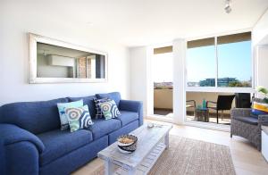 a living room with a blue couch and a table at Bondi Aqua Vista - Walk to beach and shops in Sydney