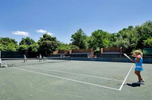 a young girl holding a tennis racket on a tennis court at Gated Gulf Front Condo in Hidden Dunes Beach & Tennis Resort in Destin