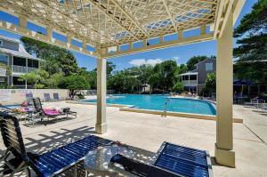 a swimming pool with blue chairs and a pergola at Gated Gulf Front Condo in Hidden Dunes Beach & Tennis Resort in Destin