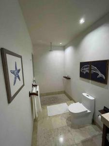 a bathroom with a toilet and paintings on the wall at El Nido Casa 4 - Paradise on the Bay in Zihuatanejo