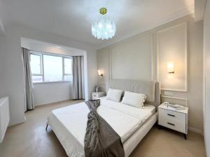 a bedroom with a large white bed with a chandelier at Warm Four Bedroom Apartment with Huangpu River View in Shanghai