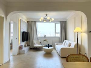 a white living room with a couch and a tv at Warm Four Bedroom Apartment with Huangpu River View in Shanghai