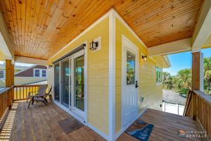 una casa pequeña con porche y techo de madera en Lovely Guesthouse Loft with Balcony and Hammock STEPS from the Beach! en New Smyrna Beach