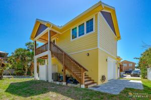 a yellow house with a staircase in a yard at Lovely Guesthouse Loft with Balcony and Hammock STEPS from the Beach! in New Smyrna Beach