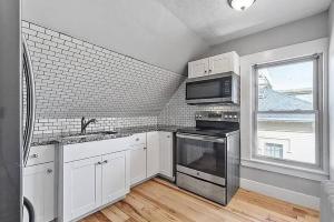 a kitchen with white cabinets and a microwave and a window at Guest suite in historical district in Gloucester