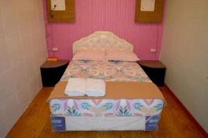 a bed in a room with a pink wall at MOJOKERTO GUESTHOUSE in Mojokerto