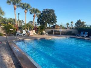 uma grande piscina com palmeiras e cadeiras em Family-Friendly DIsney Getaway em Kissimmee