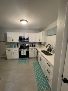 uma cozinha com armários brancos, um lavatório e um fogão em Family-Friendly DIsney Getaway em Kissimmee
