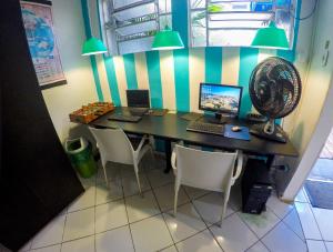 a desk with a computer and a fan and chairs at Vila Rock Hostel - próximo Allianz Parque, Vila Madalena, Av Paulista, Hospital das Clínicas INCOR FMUSP in São Paulo
