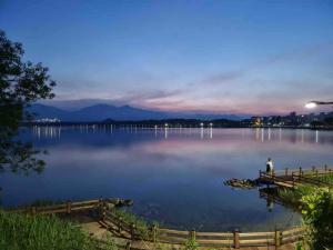 a man sitting on a dock on a lake at night at Lakestone&Hotel Sokcho in Sokcho