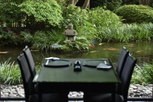 une table et des chaises en face d'un étang avec une lanterne dans l'établissement Royal Park Hotel, à Tokyo