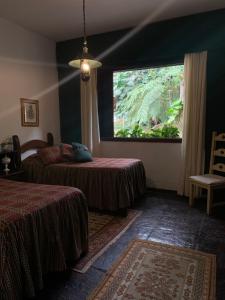 Una habitación con dos camas y una gran ventana. en Casa com cachoeira e rio particular, en Petrópolis