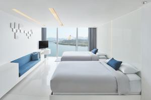 a white bedroom with two beds and a television at Vista Walkerhill Seoul - formerly W Seoul in Seoul