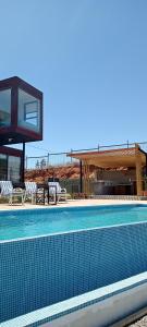 a large swimming pool with chairs and a house at Casa COSMOS golf. in Algarrobo